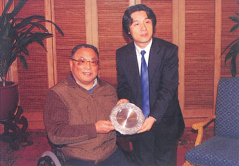 2005年11月，中国残疾人联合会主席邓普方为王虎鸣颁发“爱心形象大使”荣誉称号。